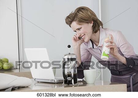 young woman at morning talking on telephone holding baby bottle and working with computer View Large Photo Image Stock Image - young woman at morning talking on telephone holding baby bottle and working with computer. Fotosearch