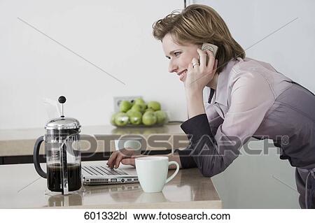 young woman at morning talking on telephone and working with computer View Large Photo Image Stock Image - young woman at morning talking on telephone and working with computer. Fotosearch