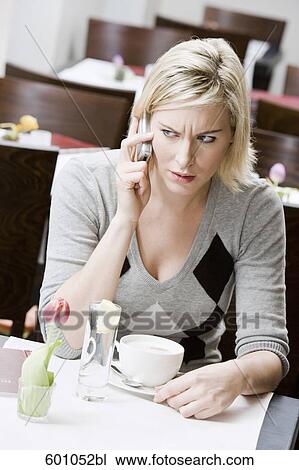 young woman sitting at restaurant table talking on mobile phone View Large Photo Image Stock Image - young woman sitting at restaurant table talking on mobile phone. Fotosearch