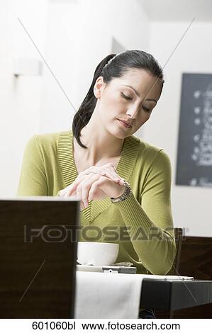 young woman sitting at restaurant table looking at her watch View Large Photo Image Stock Image - young woman sitting at restaurant table looking at her watch. Fotosearch