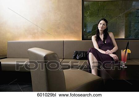 Stock Image - young woman sitting in bar waiting. Fotosearch