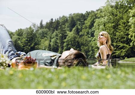 young woman watching the sky while her boyfriend is sleeping in grass View Large Photo Image Stock Image - young woman watching the sky while her boyfriend is sleeping in grass. Fotosearch