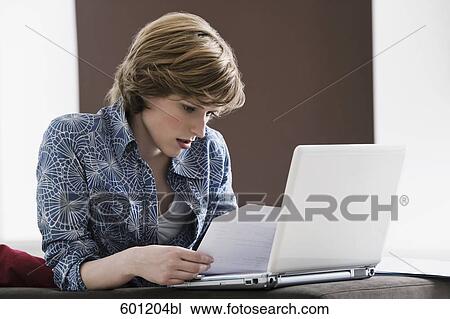 young woman with laptop computer at home reading document View Large Photo Image Stock Image - young woman with laptop computer at home reading document. Fotosearch