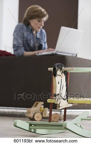young woman working with laptop computer at home rocking horse in foreground View Large Photo Image Stock Image - young woman working with laptop computer at home rocking horse in foreground. Fotosearch