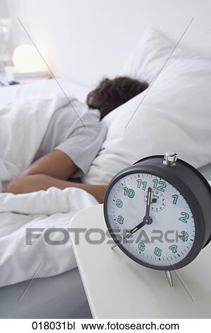 alarm clock on sideboard with woman sleeping in bed View Large Photo Image Stock Image - alarm clock on sideboard with woman sleeping in bed. Fotosearch