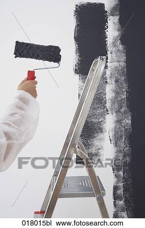 Stock Image - detail of woman painting wall blu with paint roller. Fotosearch