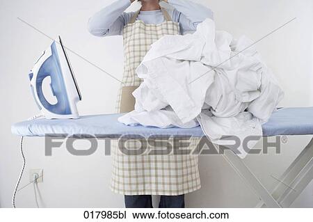 detail of woman standing behind ironing board with pile of white laundry View Large Photo Image Stock Image - detail of woman standing behind ironing board with pile of white laundry. Fotosearch