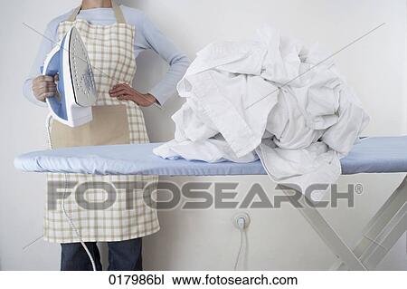 detail of woman standing behind ironing board with pile of white laundry View Large Photo Image Stock Image - detail of woman standing behind ironing board with pile of white laundry. Fotosearch