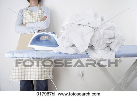 detail of woman standing behind ironing board with pile of white laundry View Large Photo Image Stock Image - detail of woman standing behind ironing board with pile of white laundry. Fotosearch