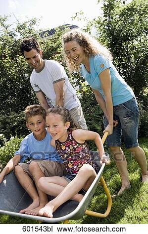 father and mother carrying their little children in wheelbarrow View Large Photo Image Stock Image - father and mother carrying their little children in wheelbarrow. Fotosearch