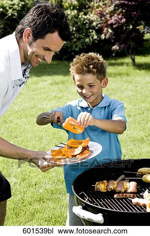 father and son grilling together at barbecue View Large Photo Image Stock Image - father and son grilling together at barbecue. Fotosearch