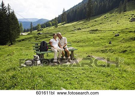 full body portrait of mature couple with dog sitting on bench in the mountains View Large Photo Image Stock Image - full body portrait of mature couple with dog sitting on bench in the mountains. Fotosearch