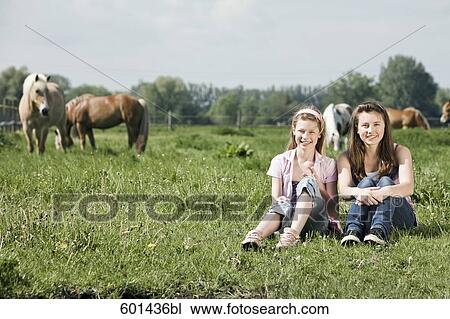 full body portrait of two girls sitting on meadow at horse ranch View Large Photo Image Stock Image - full body portrait of two girls sitting on meadow at horse ranch. Fotosearch