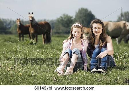full body portrait of two girls sitting on meadow at horse ranch View Large Photo Image Stock Image - full body portrait of two girls sitting on meadow at horse ranch. Fotosearch