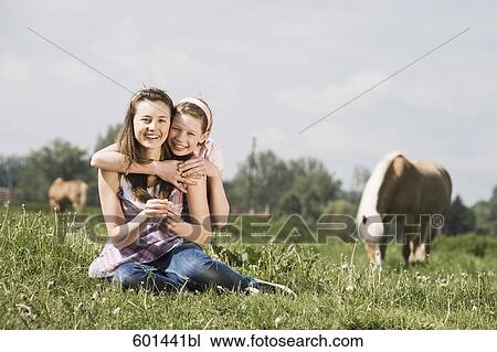 full body portrait of two girls sitting on meadow at horse ranch View Large Photo Image Stock Image - full body portrait of two girls sitting on meadow at horse ranch. Fotosearch
