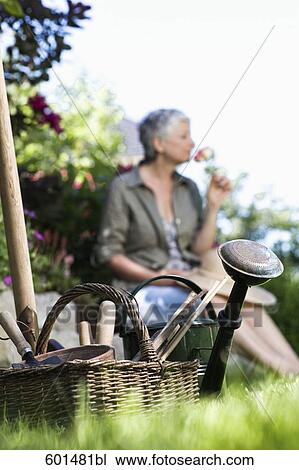 gardening equipment with woman relaxing in background View Large Photo Image Stock Image - gardening equipment with woman relaxing in background. Fotosearch