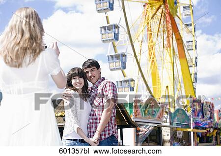 Stock Image - girl taking picture of teenage couple. Fotosearch