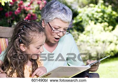 grandmother sitting in garden reading from book to little girl View Large Photo Image Stock Image - grandmother sitting in garden reading from book to little girl. Fotosearch