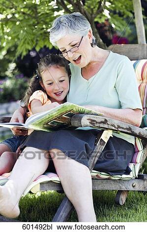 grandmother sitting in garden reading from book to little girl View Large Photo Image Stock Image - grandmother sitting in garden reading from book to little girl. Fotosearch