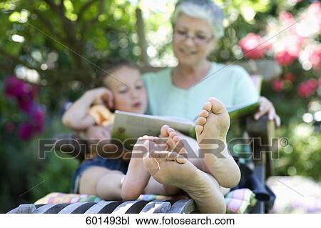 grandmother sitting in garden reading from book to little girl View Large Photo Image Stock Image - grandmother sitting in garden reading from book to little girl. Fotosearch