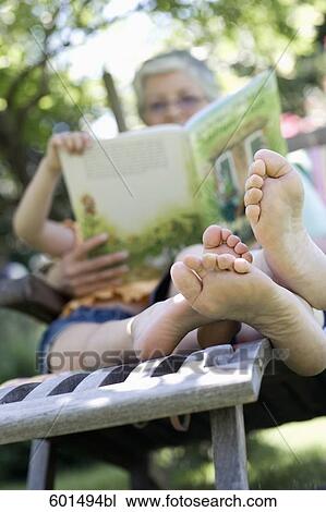 grandmother sitting in garden reading from book to little girl View Large Photo Image Stock Image - grandmother sitting in garden reading from book to little girl. Fotosearch