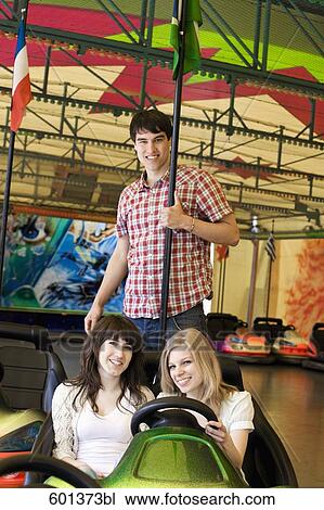 Stock Image - group of three teenagers sitting in bumper cars. Fotosearch