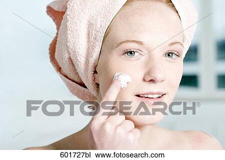 headshot of young woman applying skin cream on face View Large Photo Image Stock Image - headshot of young woman applying skin cream on face. Fotosearch