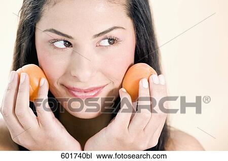 headshot of young woman holding peaches against her cheek View Large Photo Image Stock Image - headshot of young woman holding peaches against her cheek. Fotosearch