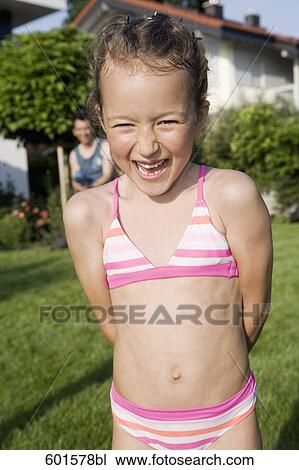 Stock Image - little girl standing in garden laughing. Fotosearch