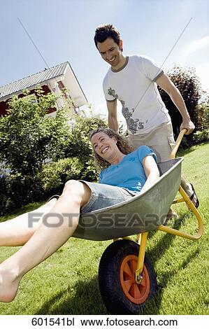 Stock Image - man carrying his wife in wheelbarrow. Fotosearch