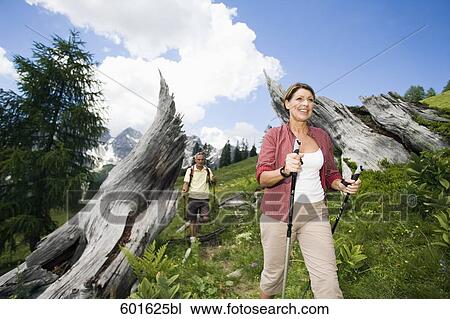Stock Image - mature couple doing nordic walking in the mountains. Fotosearch