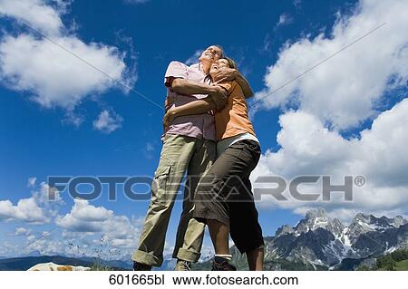 mature couple standing on rock in the mountains embracing each other View Large Photo Image Stock Image - mature couple standing on rock in the mountains embracing each other. Fotosearch