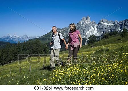 Stock Image - mature couple walking hand in hand in the mountains. Fotosearch