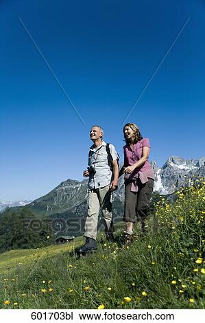 Stock Image - mature couple walking hand in hand in the mountains. Fotosearch