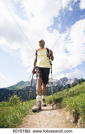 Stock Image - mature man doing nordic walking in the mountains. Fotosearch