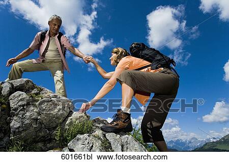 mature man helping woman to climb rock in the mountains View Large Photo Image Stock Image - mature man helping woman to climb rock in the mountains. Fotosearch