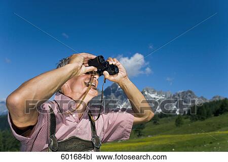 mature man in the mountains looking through binoculars View Large Photo Image Stock Image - mature man in the mountains looking through binoculars. Fotosearch