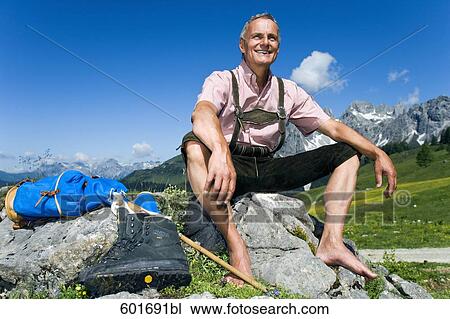 mature man sitting barefoot on rock in the mountains View Large Photo Image Stock Image - mature man sitting barefoot on rock in the mountains. Fotosearch
