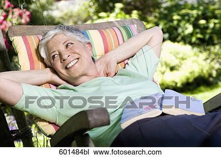 mature woman relaxing on deck chair in garden View Large Photo Image Stock Image - mature woman relaxing on deck chair in garden. Fotosearch