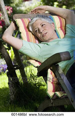 mature woman relaxing on deck chair in garden View Large Photo Image Stock Image - mature woman relaxing on deck chair in garden. Fotosearch