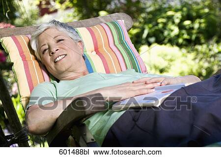 mature woman relaxing on deck chair in garden View Large Photo Image Stock Image - mature woman relaxing on deck chair in garden. Fotosearch