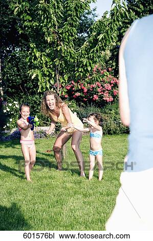 Stock Image - mother playing in garden with her two little daughters. Fotosearch
