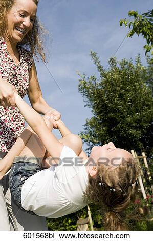 Stock Image - mother playing with little girl in garden. Fotosearch