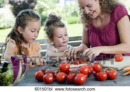 mother showing her two daughters how to make salad of tomatoes View Large Photo Image Stock Image - mother showing her two daughters how to make salad of tomatoes. Fotosearch