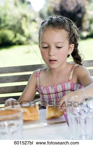 portrait of little girl sitting at table in garden with bread View Large Photo Image Stock Image - portrait of little girl sitting at table in garden with bread. Fotosearch