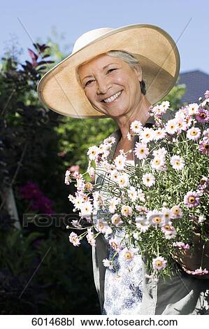 portrait of mature woman in gardening outfit holding flowers View Large Photo Image Stock Image - portrait of mature woman in gardening outfit holding flowers. Fotosearch