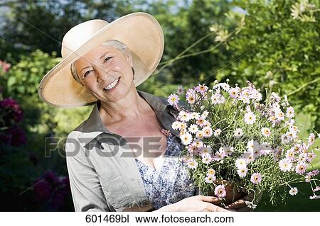 portrait of mature woman in gardening outfit holding flowers View Large Photo Image Stock Image - portrait of mature woman in gardening outfit holding flowers. Fotosearch