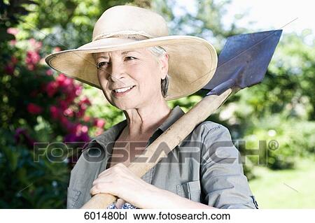 portrait of mature woman in gardening outfit carrying spade View Large Photo Image Stock Image - portrait of mature woman in gardening outfit carrying spade. Fotosearch