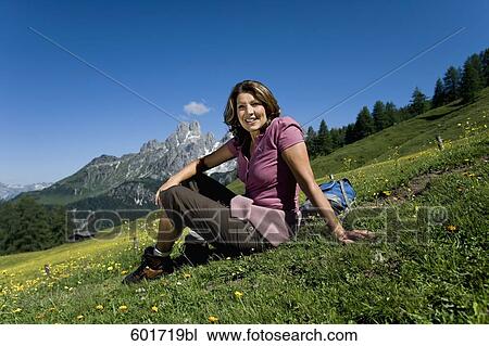 Stock Image - portrait of mature woman relaxing on meadow in the mountains. Fotosearch