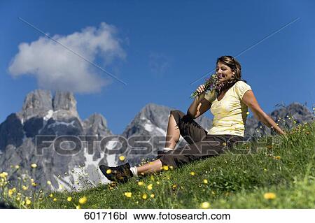 Stock Image - portrait of mature woman sitting in summer meadow. Fotosearch